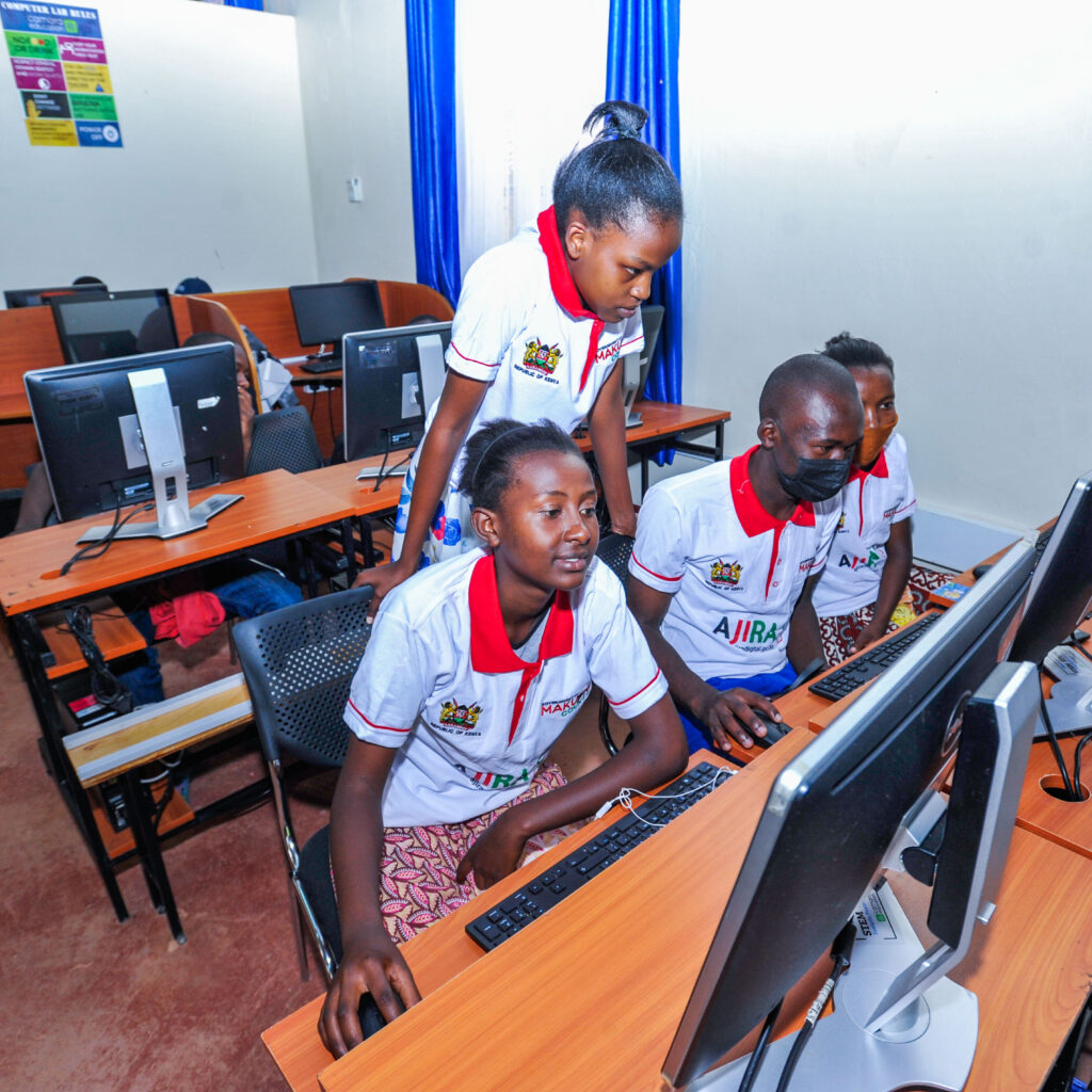 Young people taking part in a computer skills training session in a classroom.